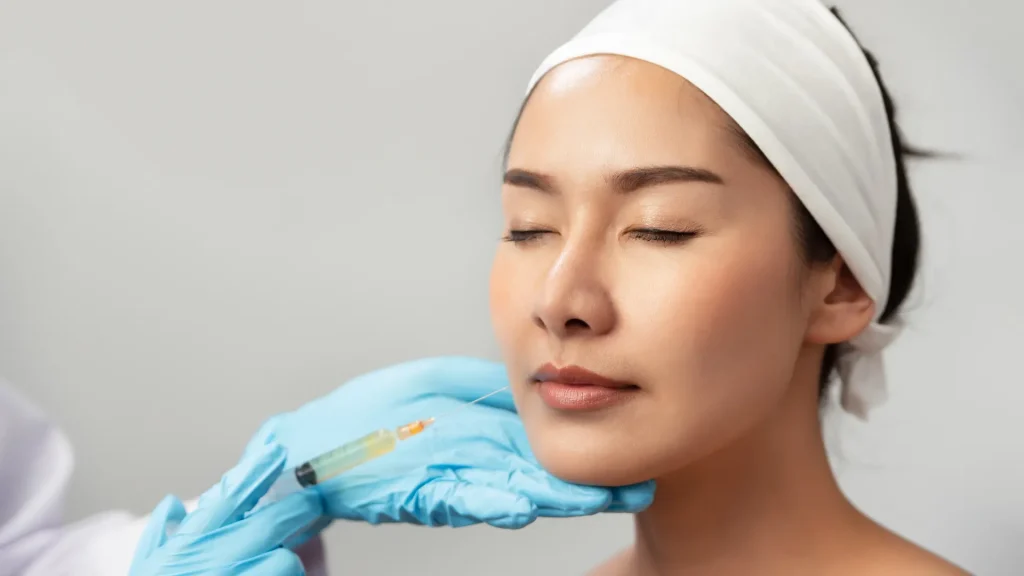 A medical professional administering a facial injection to a patient.