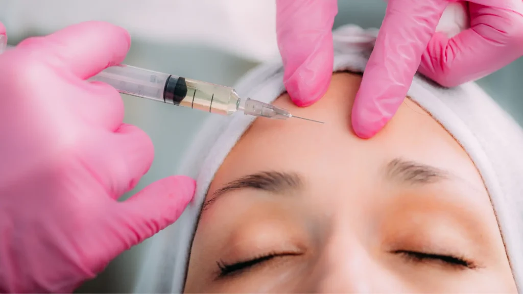 A medical professional administering an injection to treat the patient's forehead lines.