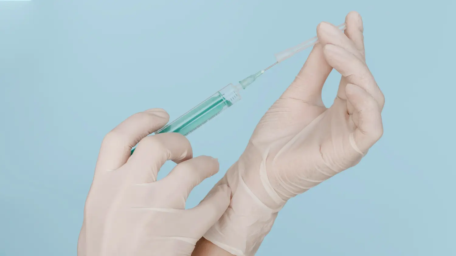 A medical professional transferring the vial's content into the syringe.