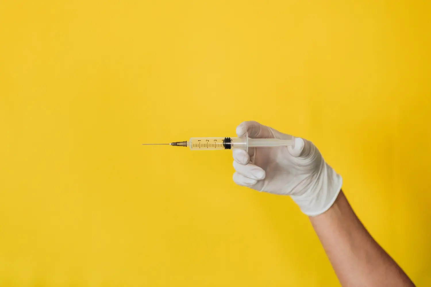 A healthcare provider holding a medical syringe.