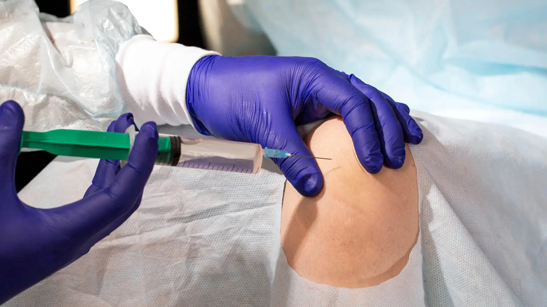 A medical professional administering a knee injection.