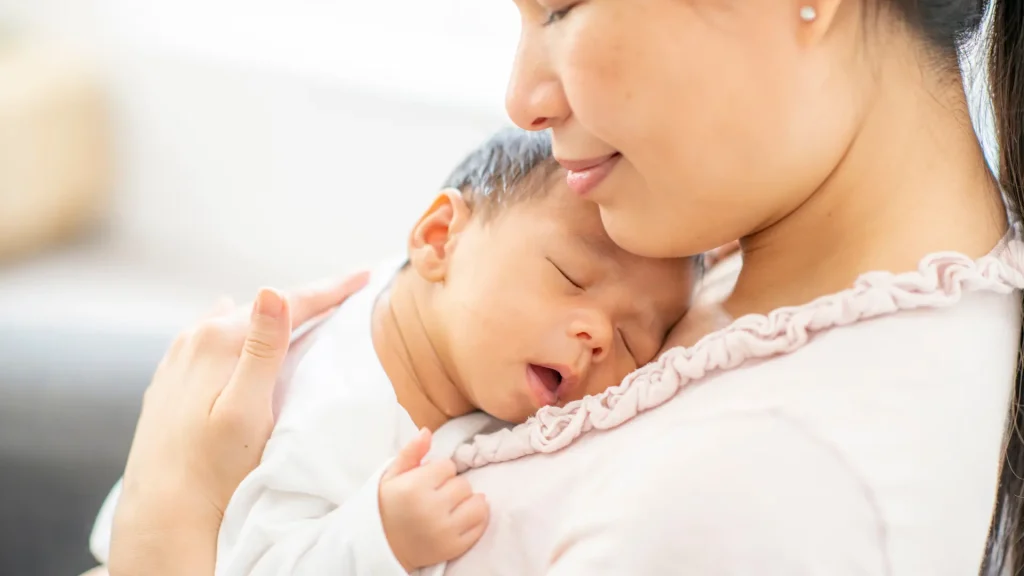 A mother holding her sleeping newborn.