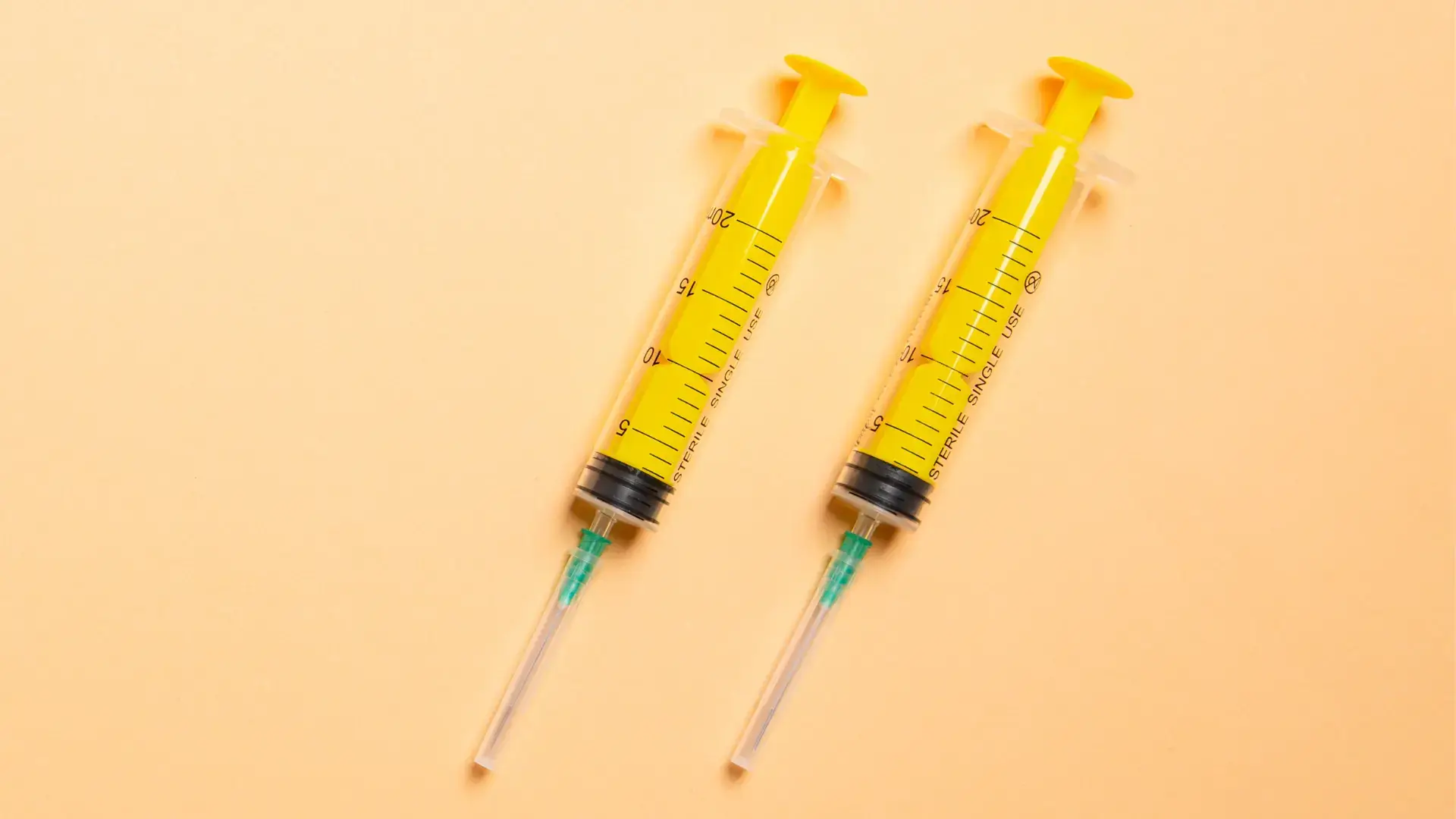 Two medical syringes on a surface.