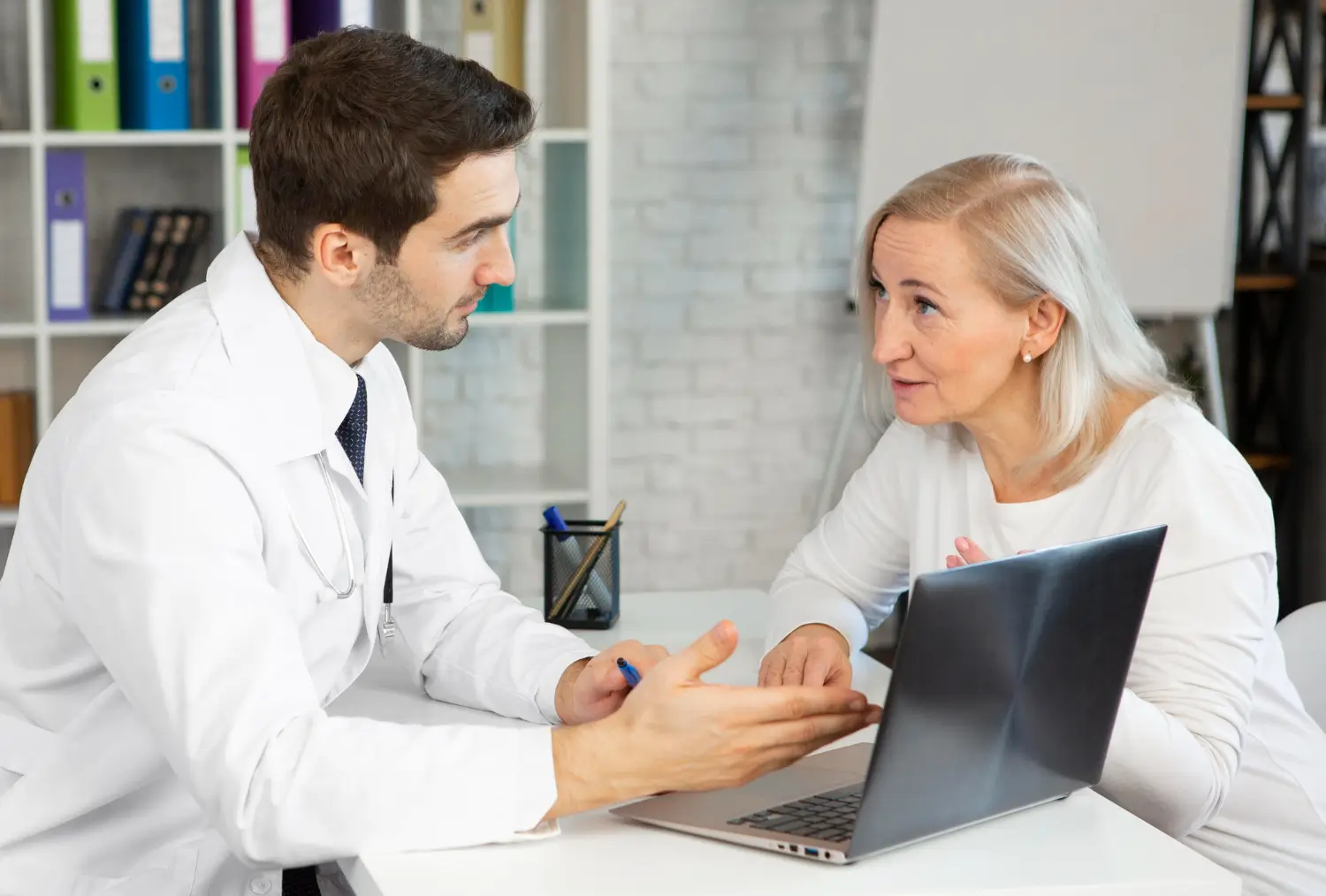 A male doctor discussing a treatment to an older woman patient.