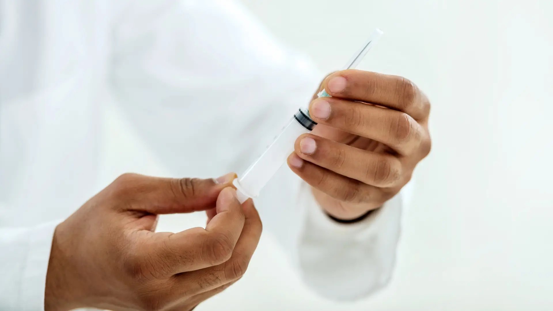 A healthcare provider preparing a medical syringe.