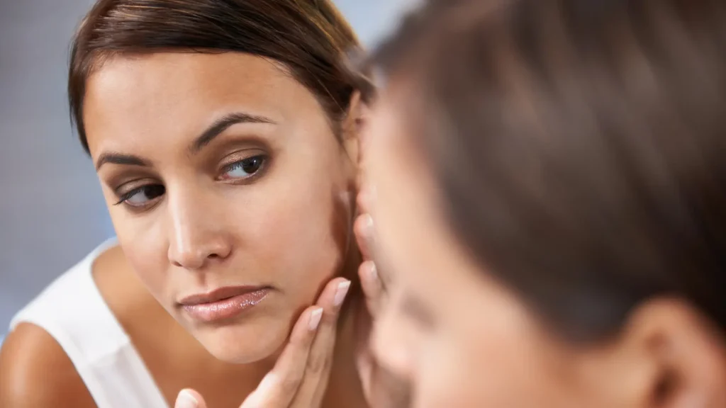 An individual checking their jawline region in the mirror.