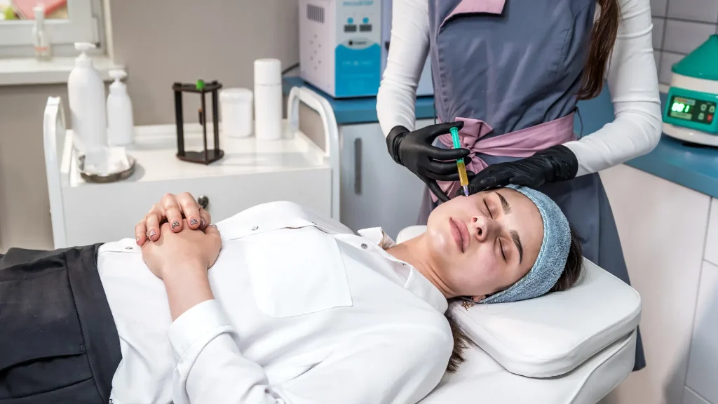 An aesthetic provider administering a cheek injection into the patient.