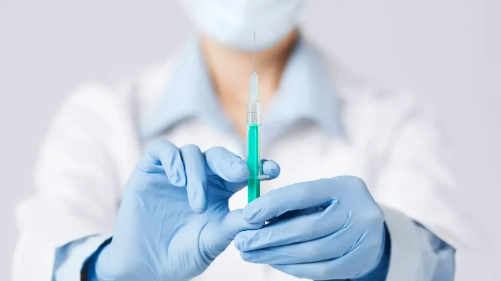 A medical professional holding a medical syringe.