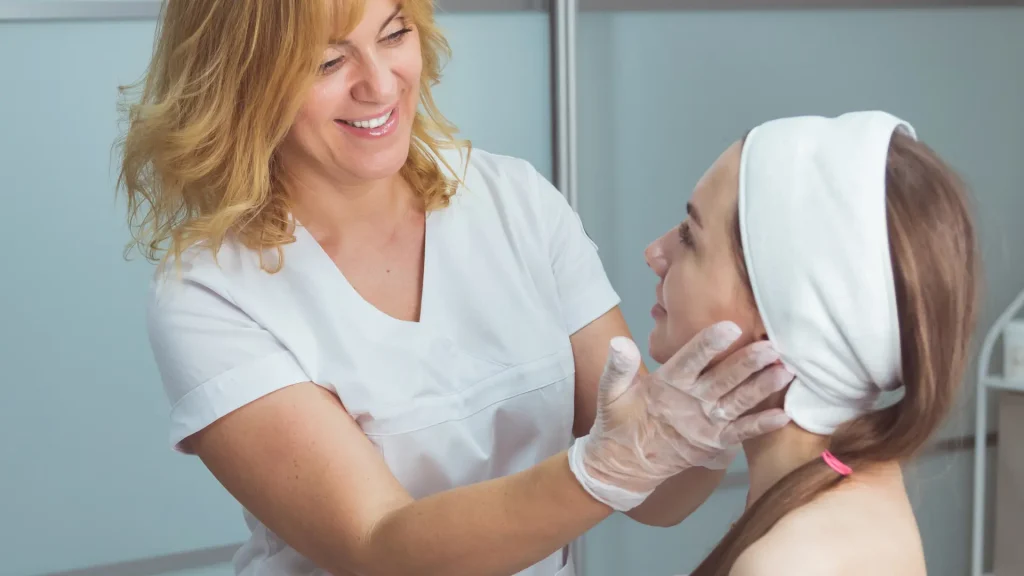 An aesthetic professional examining the patient's face post-treatment.