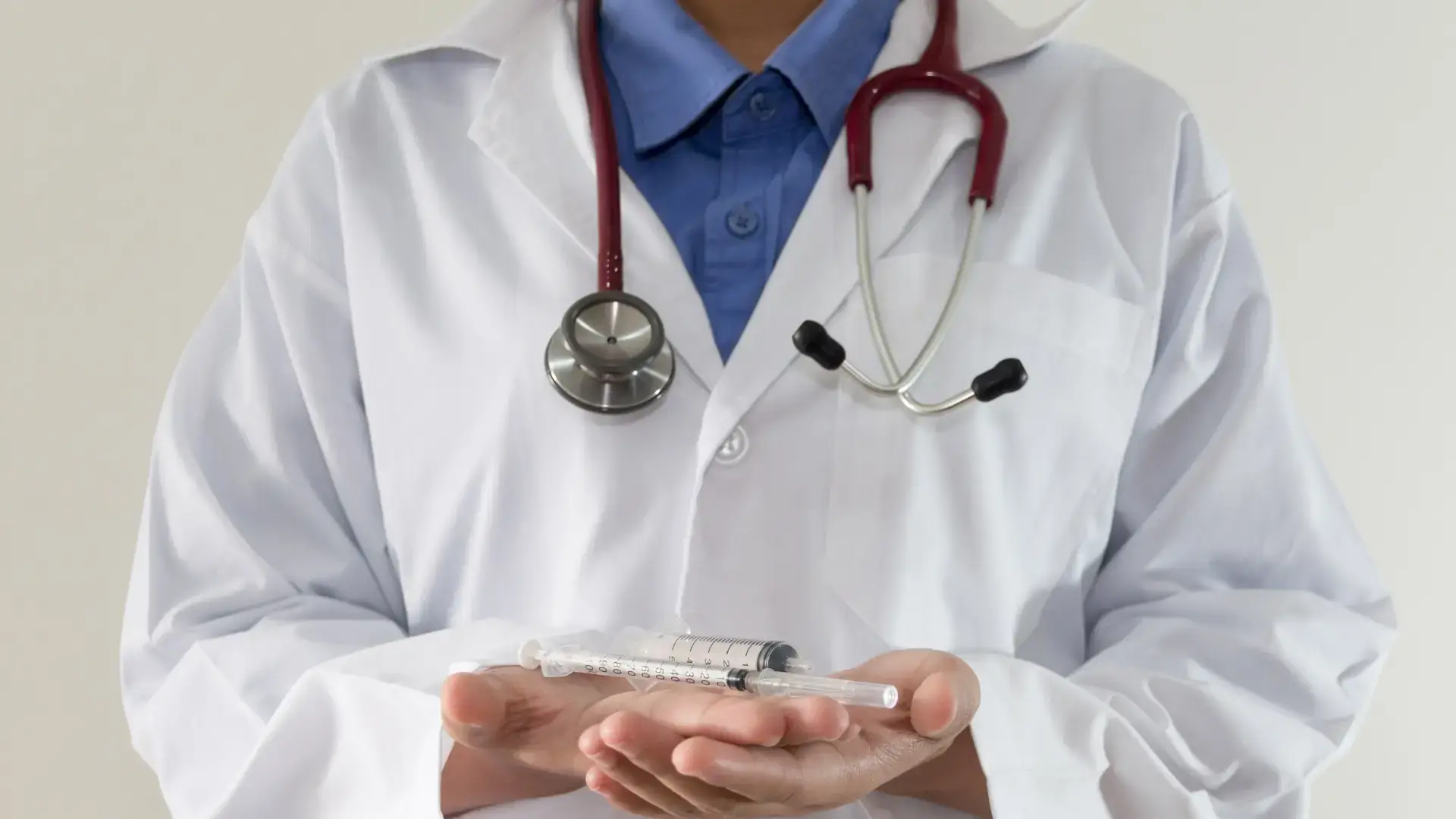 A medical professional holding a medical syringe.