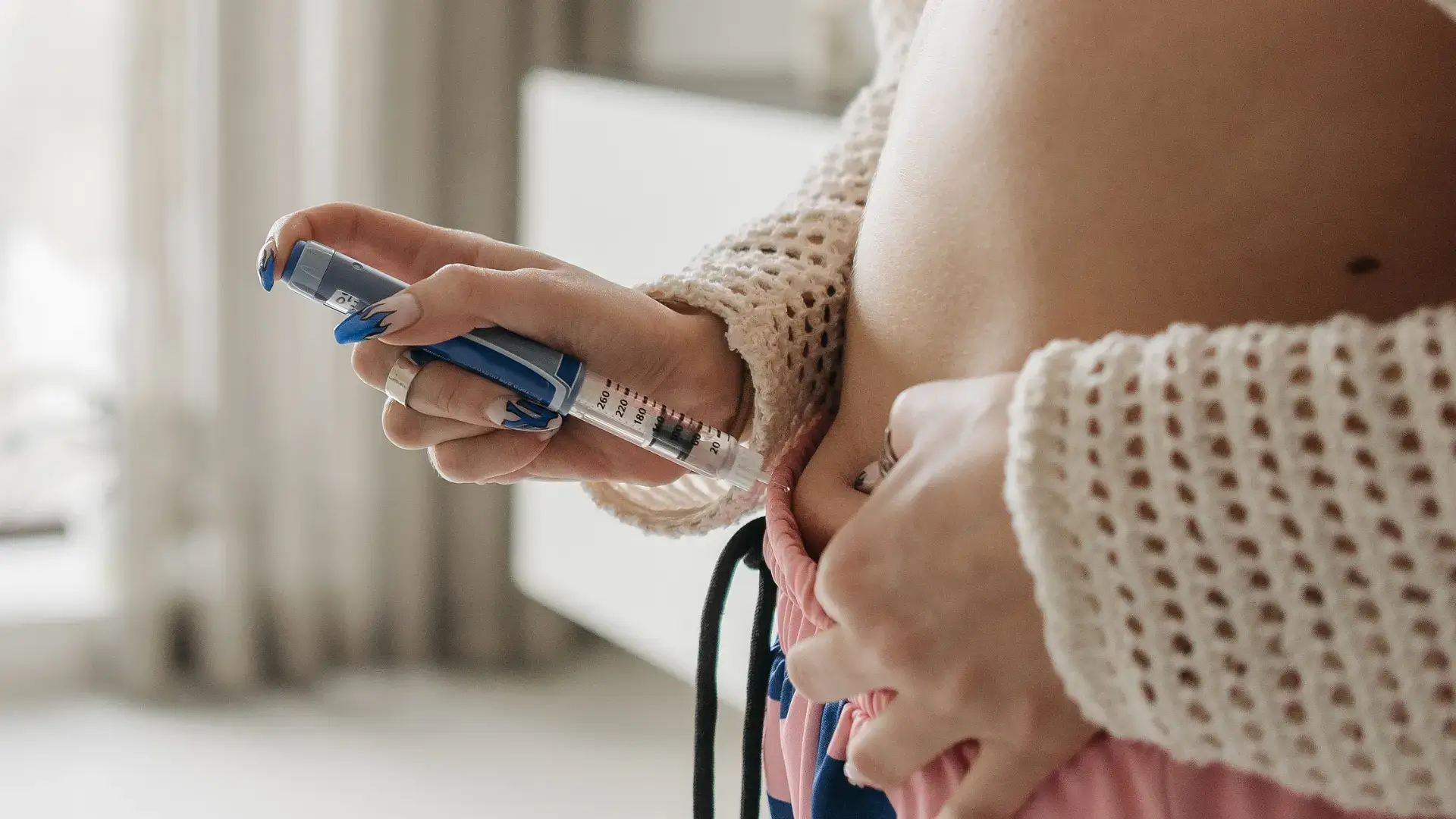 An individual administering an injection into their abdomen.