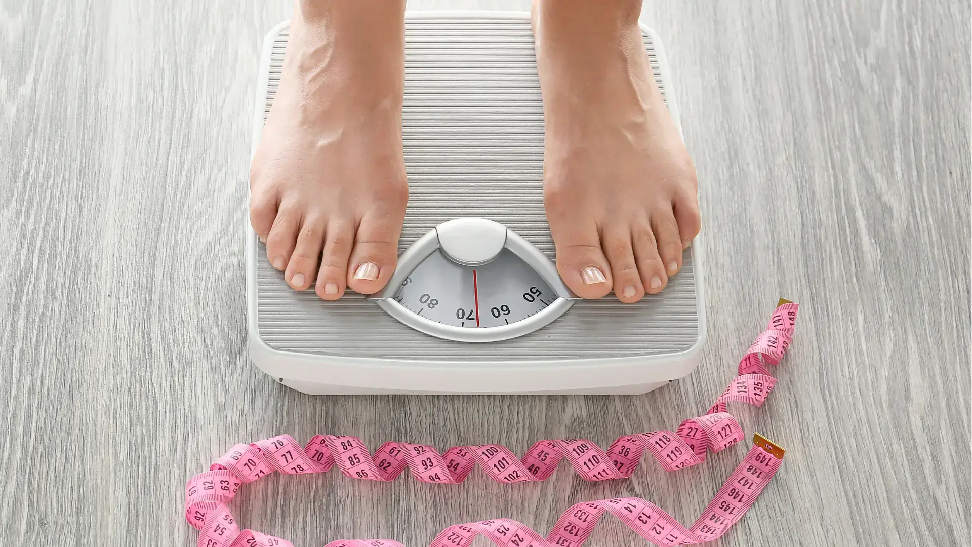 An individual weighing their weight on a scale.