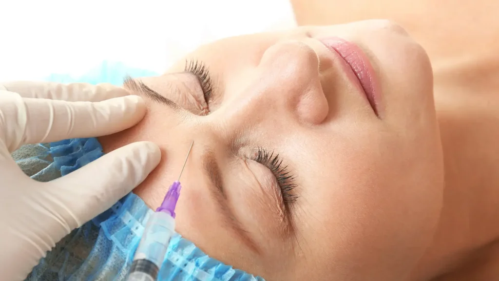 A healthcare provider injecting into the patient's forehead area.