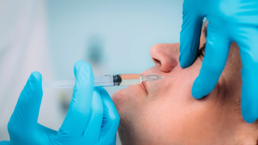 A patient undergoing a cheek injection administered by an aesthetic professional.